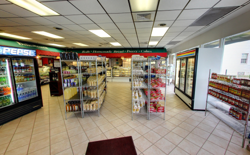 Interior of a small grocery store featuring shelves of snacks, drinks, and baked goods in a bright, clean space.