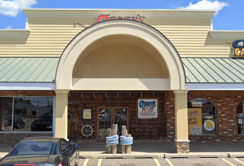 Exterior of O'Brien's restaurant featuring a large archway entrance and a sign, with a brick facade and parking in front.