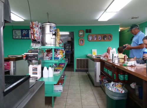 A cozy diner interior with a snack counter, tables, and patrons enjoying their meals in a turquoise-themed space.