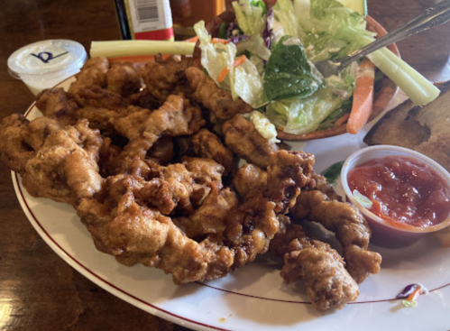 A plate of crispy fried food with a side salad and dipping sauce.