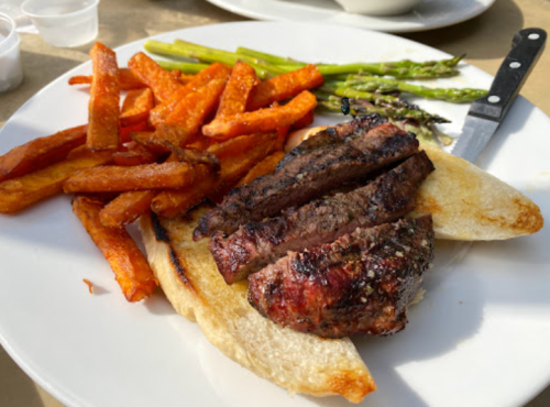 A plate with grilled steak slices on toast, sweet potato fries, and asparagus.