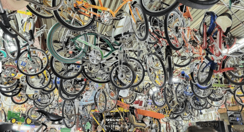 A ceiling filled with various bicycles and bike parts, creating a colorful and chaotic display.