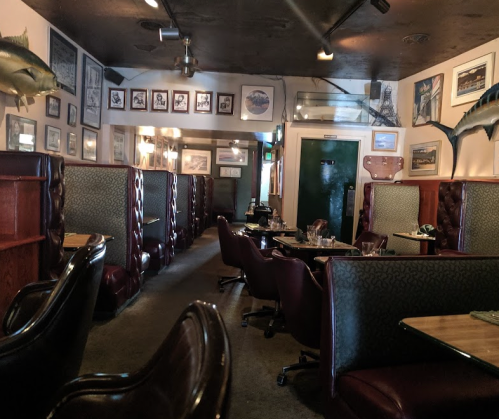 Interior of a cozy restaurant featuring booths, tables, and framed artwork on the walls.
