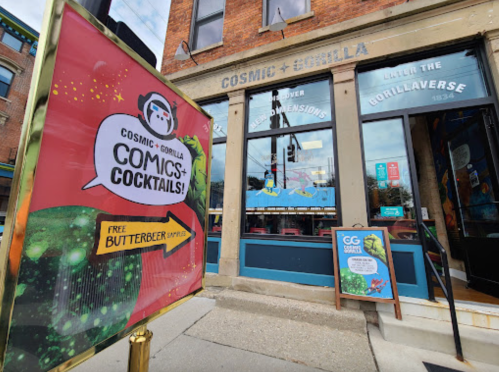 A colorful sign for "Cosmic + Gorilla" advertises comics and cocktails outside a vibrant storefront.