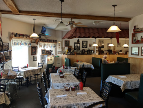 Cozy restaurant interior with tables, booths, and vintage decor, featuring a warm atmosphere and a few diners.