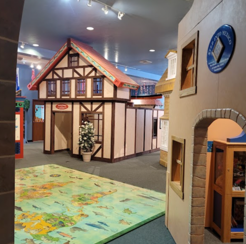 Colorful indoor play area featuring a model house and a large world map on the floor.