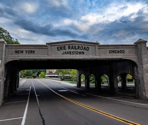 A stone bridge with "Erie Railroad Jamestown" and city names "New York" and "Chicago" inscribed above a road.