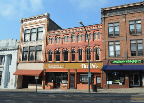 A row of historic buildings featuring restaurants and shops, with a clear blue sky above.
