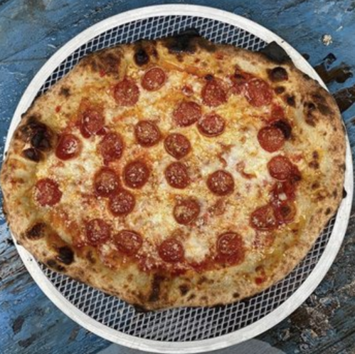 A freshly baked pepperoni pizza on a round metal tray, with a crispy crust and melted cheese.