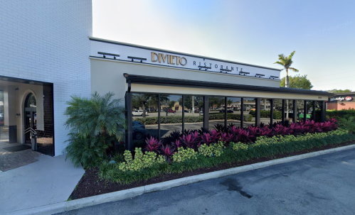 Exterior view of Divieto Ristorante, featuring a modern facade and colorful landscaping with plants.