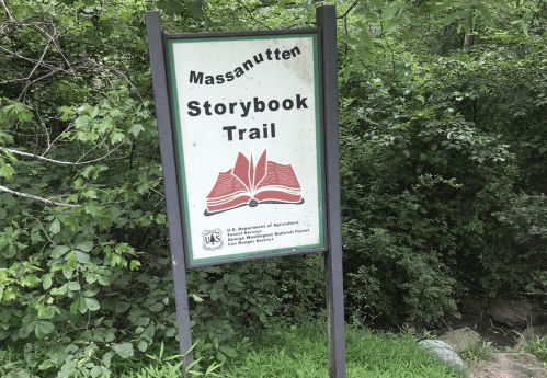 Sign for the Massanutten Storybook Trail, surrounded by greenery and trees.