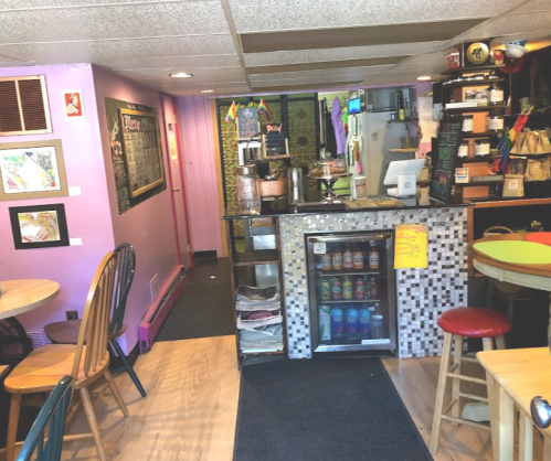 Cozy café interior with colorful walls, tables, and a counter displaying drinks and snacks.