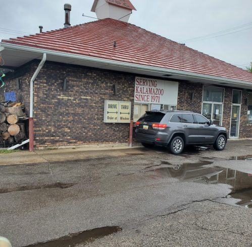 A brick building with a red roof, featuring signs for drive-thru service and "Serving Kalamazoo Since 1971."