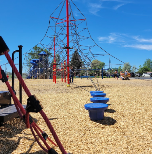 A playground with a climbing structure, blue stepping stones, and a slide under a clear blue sky.