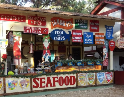 A colorful seafood stand with various menu items, festive decorations, and staff serving customers.
