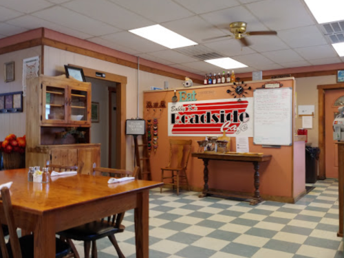 Cozy diner interior with wooden tables, checkered floor, and a colorful wall sign for "Leadside Café."