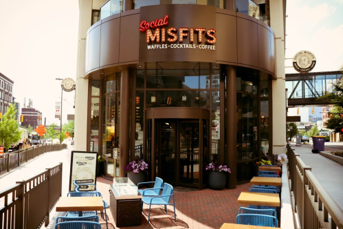 Exterior of "Social Misfits" café featuring a sign, outdoor seating, and a modern urban setting.