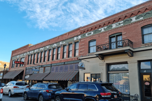 Historic Occidental Hotel with brick facade and balconies, surrounded by parked cars under a blue sky.