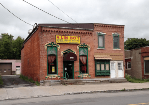 A brick building with colorful trim, featuring large windows and a sign for "Lin Boy" Chinese takeout.