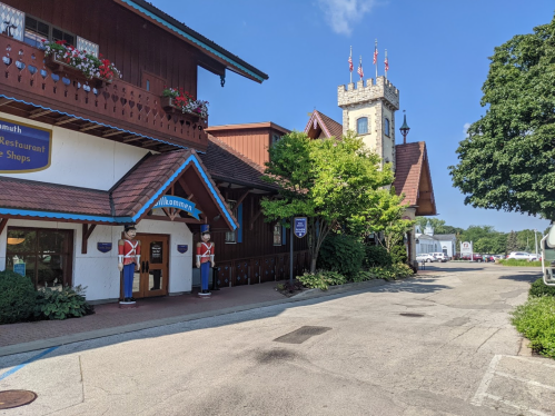 A charming building with a tower, featuring decorative flowers and toy soldier statues, set in a scenic outdoor area.