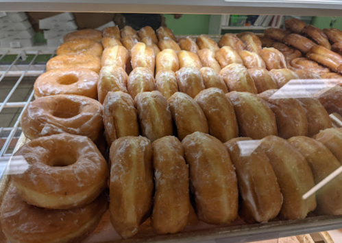 A display case filled with a variety of glazed donuts, including rings and traditional shapes.