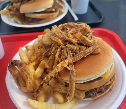 A plate with a cheeseburger topped with crispy onions, served with crinkle-cut fries on a red tray.