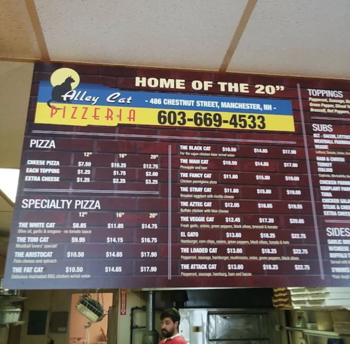 Menu board for Alley Cat Pizzeria in Manchester, NH, listing pizza and specialty pizza options with prices.