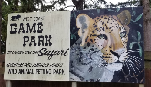 Sign for West Coast Game Park featuring a painted leopard and text about the animal petting park and safari experience.
