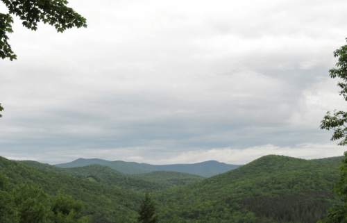 A panoramic view of lush green mountains under a cloudy sky.