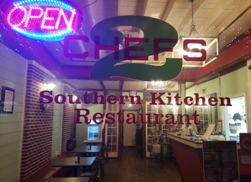 A brightly lit restaurant window displaying "Open" and "2 Chefs Southern Kitchen Restaurant" signage.