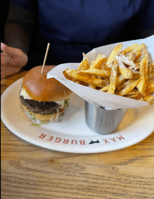 A burger with a toothpick and a side of crispy fries on a plate at a restaurant.