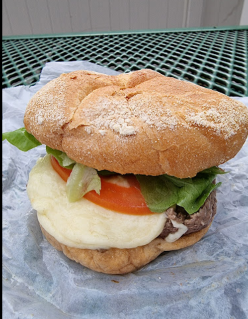 A close-up of a sandwich with a soft bun, lettuce, tomato, and a thick layer of mashed potatoes inside.