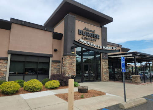 Exterior of a modern burger restaurant with a stone facade and large windows, featuring a sign that reads "Burger Company."