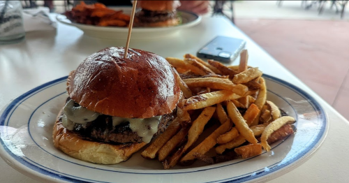 A juicy burger with melted cheese on a toasted bun, served with a side of crispy French fries.