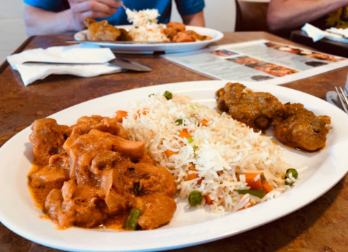 A plate of chicken curry with rice and vegetables, served in a restaurant setting.
