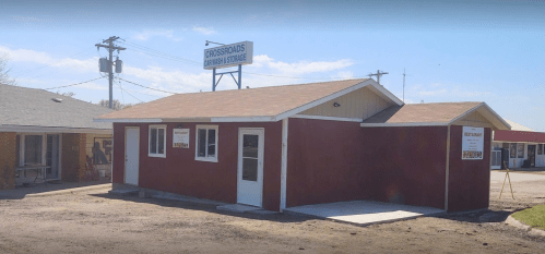 A small, red storage building with a sign reading "Crossroads RV & Mini Storage" on a sunny day.