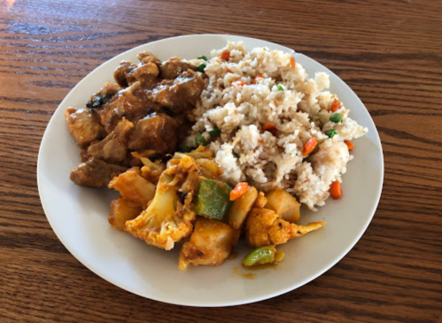 A plate of food featuring chicken in sauce, fried rice with vegetables, and a mix of spiced potatoes and cauliflower.