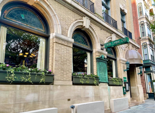 Exterior view of Union League Café, featuring arched windows, decorative planters, and historic signage.