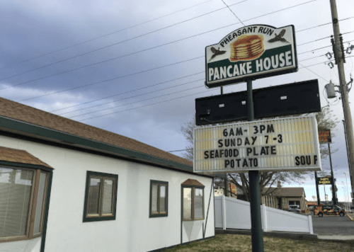 Sign for Pleasant Run Pancake House, featuring hours and Sunday special: seafood plate, potato, and soup.
