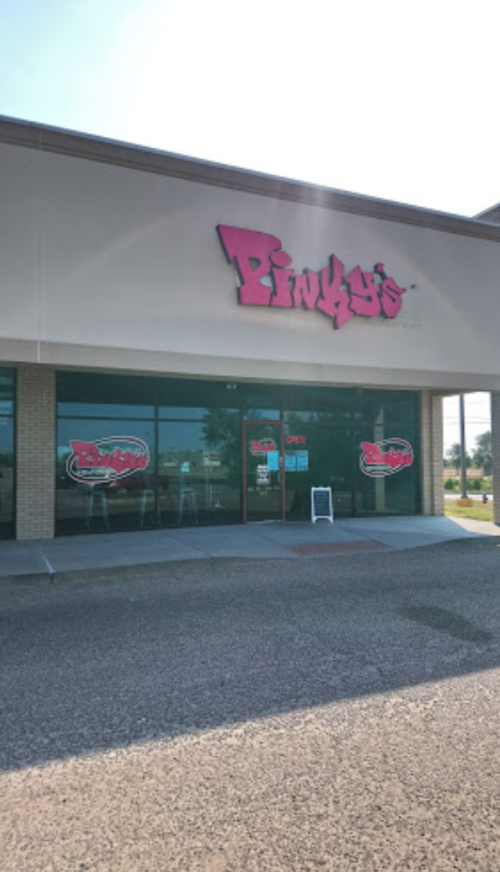 Exterior of Pinky's restaurant with a bright sign, large windows, and an open sign displayed.