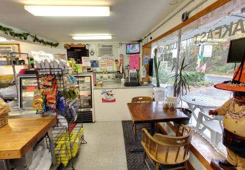 Cozy café interior with a counter, snacks display, and a view of outdoor seating through large windows.