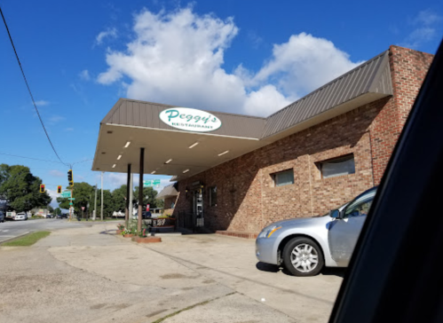 Exterior view of Peggy's Restaurant, featuring a brick facade and a clear blue sky with clouds.