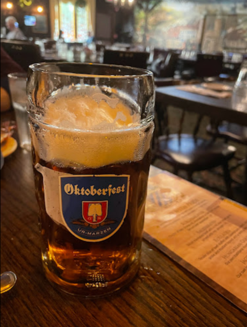 A large glass of Oktoberfest beer sits on a table in a cozy restaurant setting.