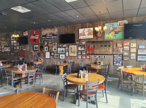 A cozy restaurant interior with wooden tables, framed artwork on the walls, and a warm, inviting atmosphere.