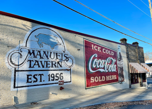 Mural on a building featuring "Manuel's Tavern" and "Ice Cold Coca-Cola Sold Here" with a vintage design.