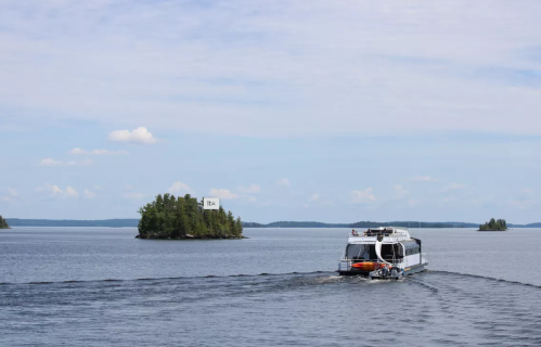 A boat navigates through calm waters, with small islands in the background under a clear blue sky.