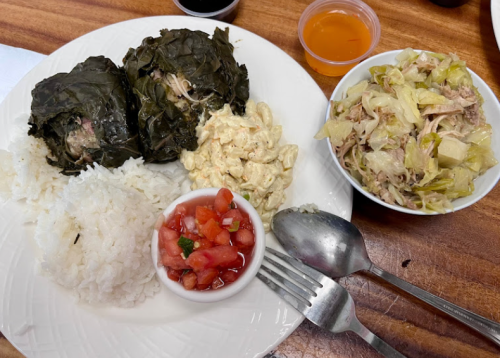 A plate with rice, two wrapped dishes, macaroni salad, fresh salsa, and a side of cabbage salad.