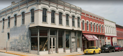 Historic buildings line a street, featuring a mix of architectural styles and a yellow taxi parked nearby.