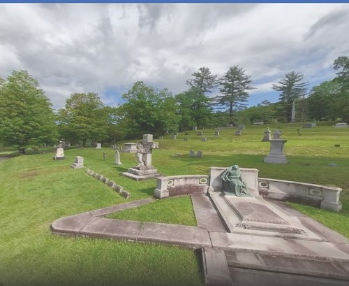 A serene cemetery scene with green grass, trees, and various gravestones under a cloudy sky.