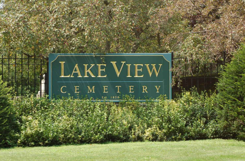 Sign for Lake View Cemetery, established in 1856, surrounded by greenery and trees.